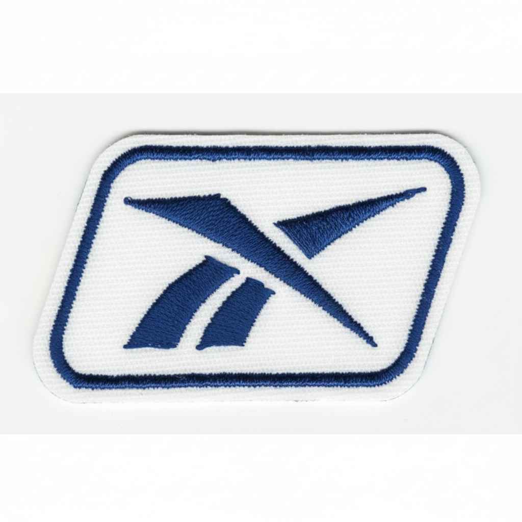 Parche bordado con logotipo azul sobre fondo blanco y borde azul rectangular con esquinas redondeadas.